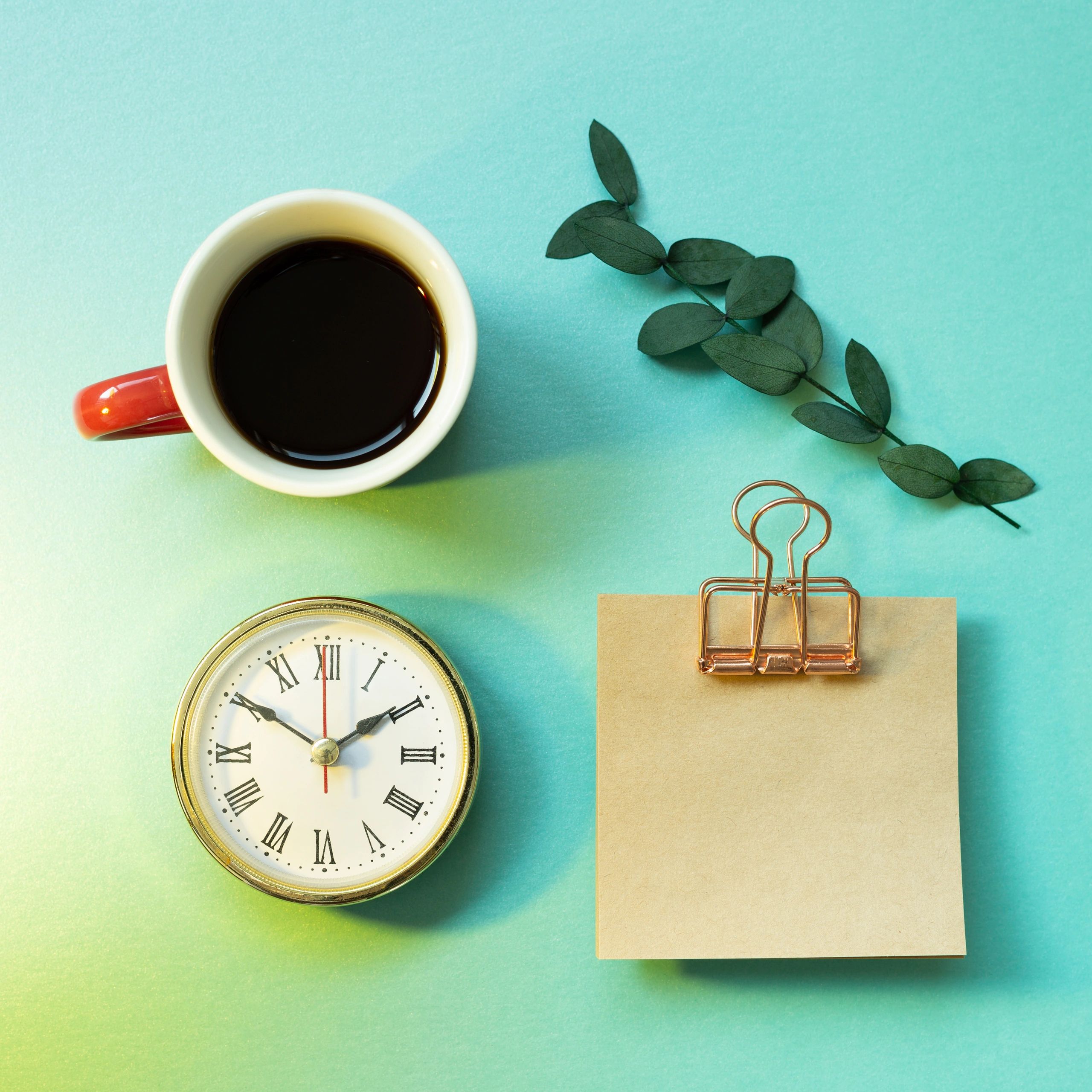Notepad, clock, cup of coffee, green leaf on mint green background. office desk, workspace. top view