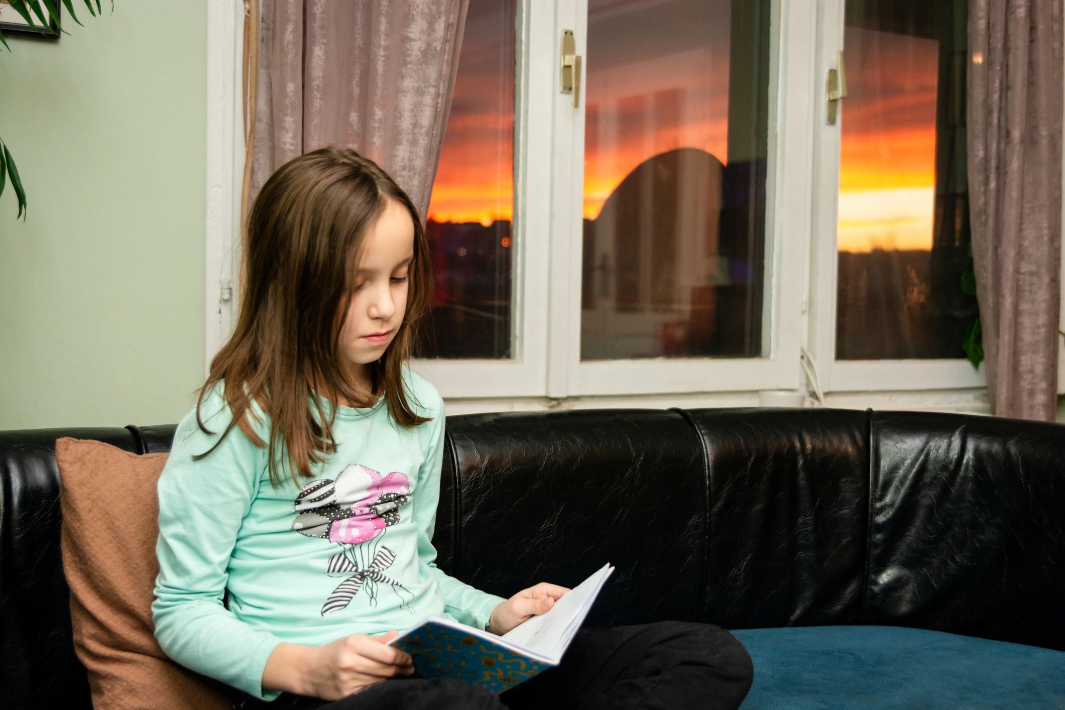 Child reading a book on a sofa