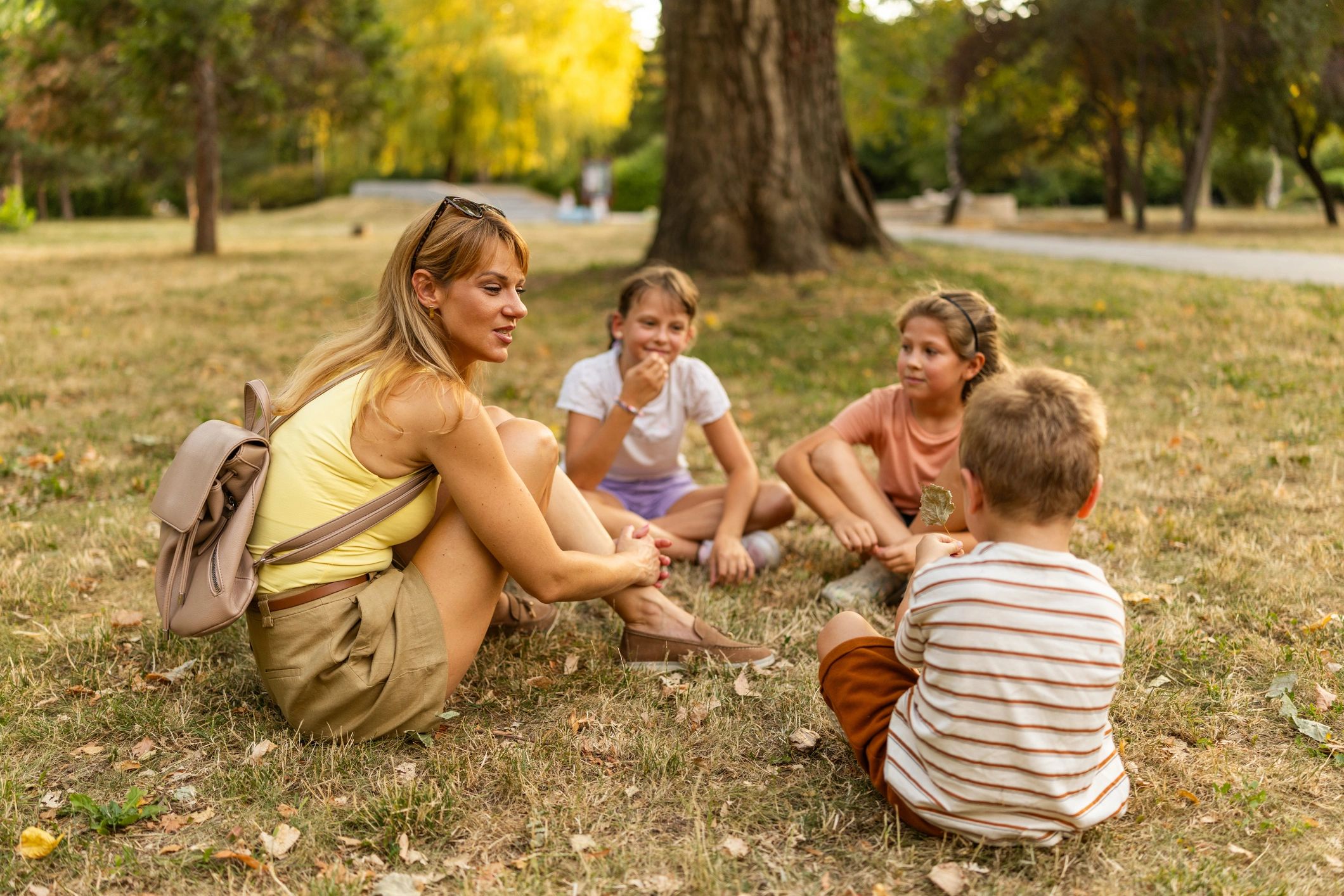 Mother and children sitting together on grass in a park