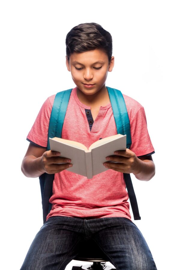 Latin schoolboy sitting and reading a book
